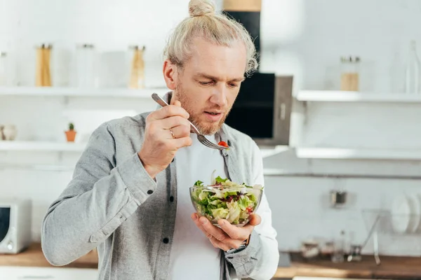 Bell'uomo adulto che mangia insalata di verdure a casa — Foto stock