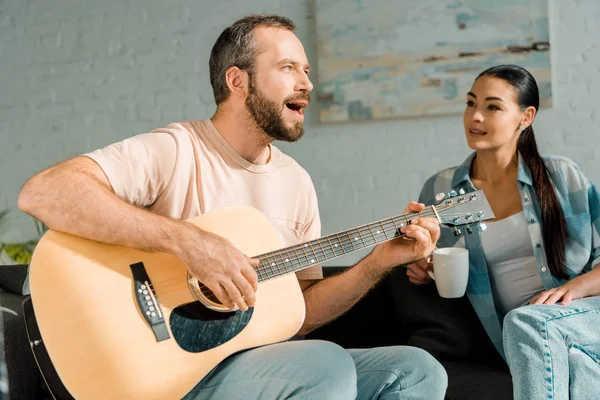 Handsome husband playing guitar and singing while wife woman listening — Stock Photo