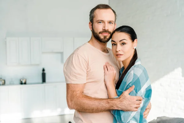 Portrait of beautiful couple embracing and looking at camera at home — Stock Photo