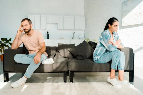 Couple having disagreement and sitting at opposite ends of sofa — Stock Photo