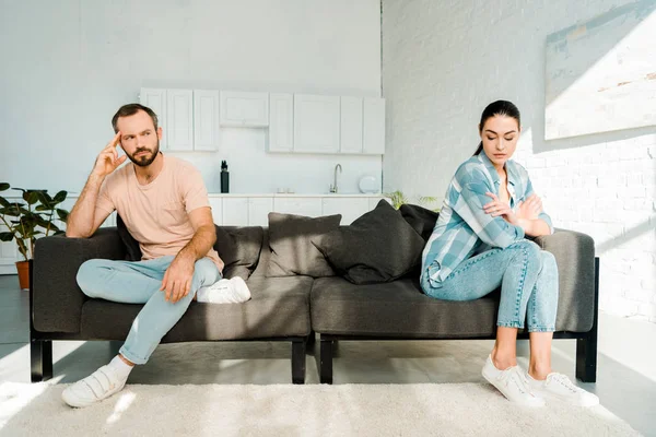 Pareja discutiendo y sentada en extremos opuestos del sofá - foto de stock