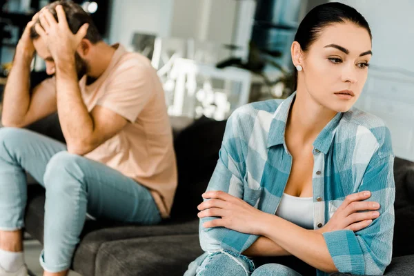 Upset couple sitting on couch after arguing at home — Stock Photo