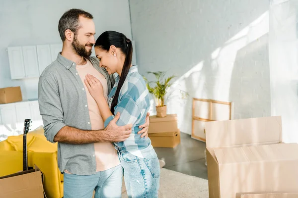 Laughing couple embracing while packing for new house, moving concept — Stock Photo