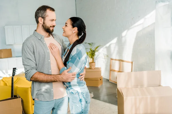 Счастливая пара обнимает во время упаковки для нового дома, движущаяся концепция — стоковое фото