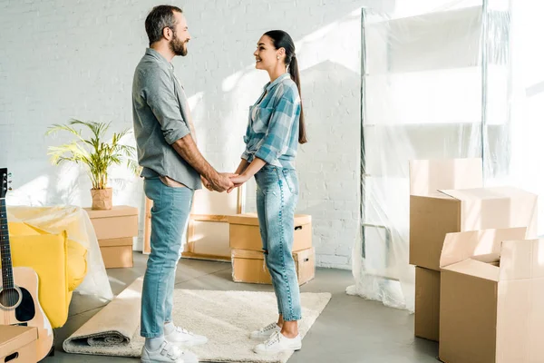 Excited couple holding hands while packing for new house, moving concept — Stock Photo