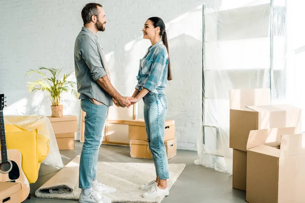 Pareja emocionada tomados de la mano mientras que el embalaje para la nueva casa, concepto móvil - foto de stock