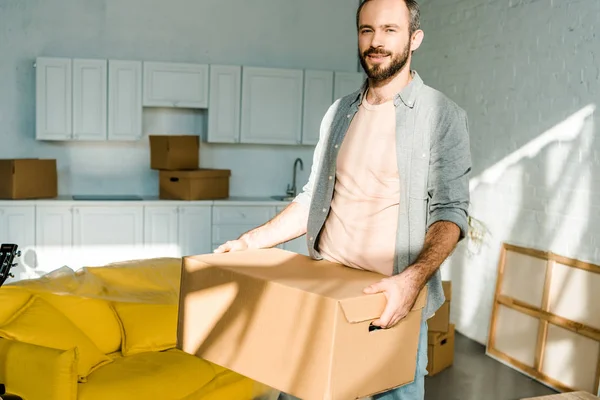 Handsome man carrying cardboard box and packing for new house, moving concept — Stock Photo