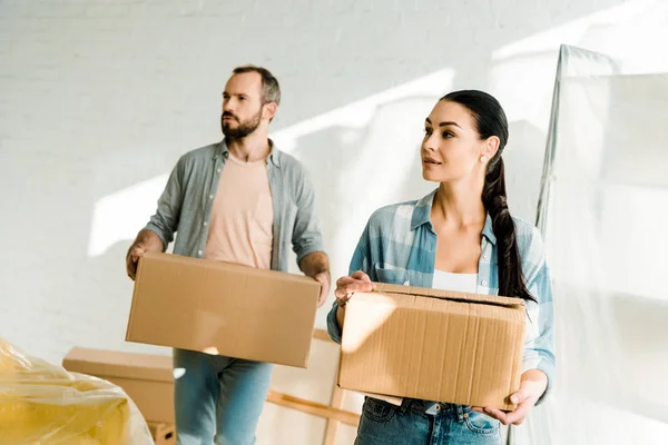 Husband and wife carrying cardboard boxes and packing for new house, moving concept — Stock Photo