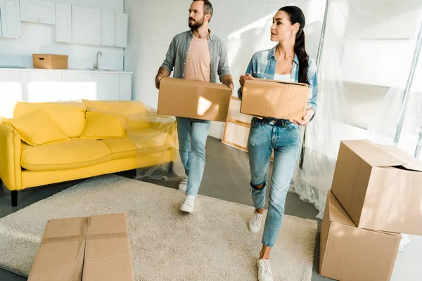 Husband and wife carrying cardboard boxes and packing for new house, moving concept — Stock Photo