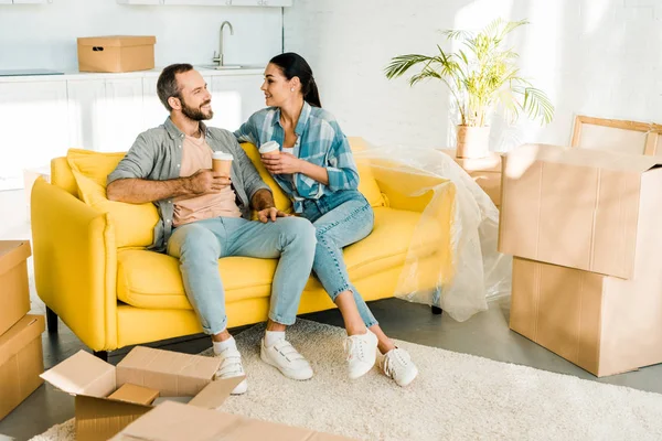 Beautiful husband and wife sitting on couch and drinking coffee while packing for new house, moving concept — Stock Photo