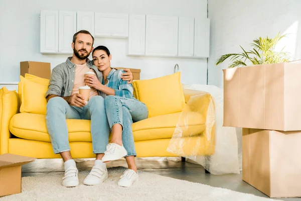 Husband and wife sitting on couch and drinking coffee while packing for new house, moving concept — Stock Photo
