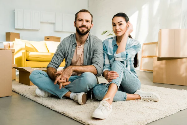 Marido y mujer sentados en el suelo y descansando después de empacar para una casa nueva, concepto móvil - foto de stock