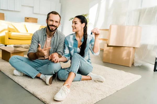 Husband pointing finger at wife holding keys from new house, moving concept — Stock Photo