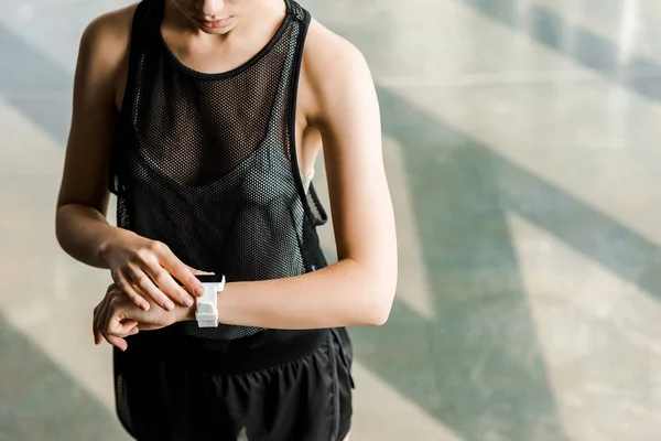 Sección media de la deportista ajustando reloj inteligente deportivo en la mano en el gimnasio - foto de stock