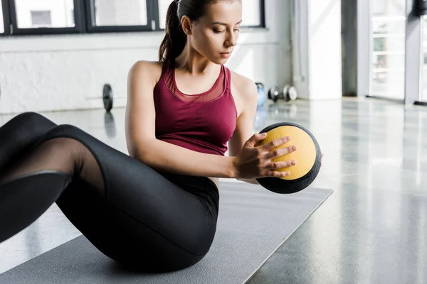 Deportista en forma enfocada haciendo ejercicio en abdominales con balón de medicina en el centro deportivo - foto de stock