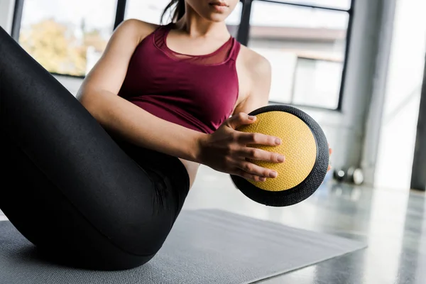 Vista recortada de la deportista haciendo ejercicio sobre abdominales con balón de medicina en el centro deportivo - foto de stock