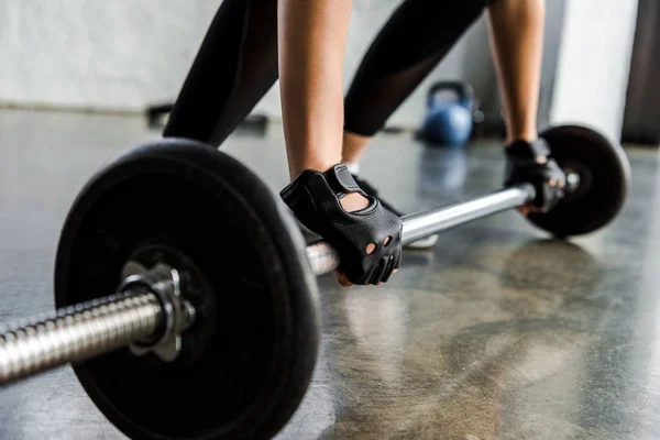 Ausgeschnittene Ansicht einer Sportlerin im Gewichtheberhandschuhtraining mit Langhantel im Fitnessstudio — Stockfoto