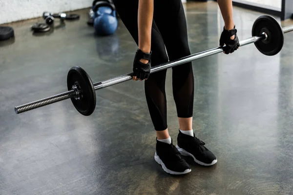 Baixa seção de esportista em treinamento luvas de levantamento de peso com barra no ginásio — Fotografia de Stock