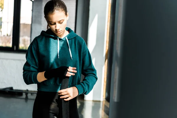 Sportiva concentrata che indossa guanti sportivi al centro fitness — Foto stock