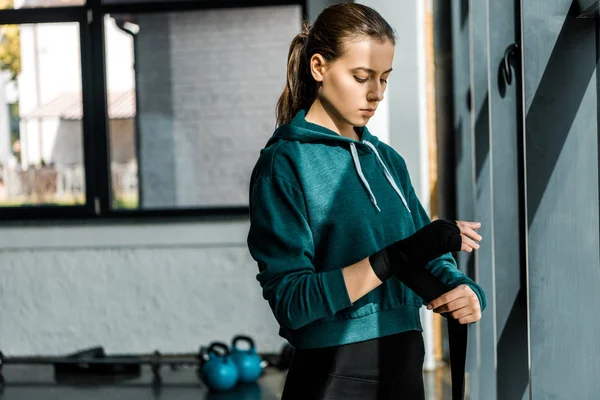 Fokussierte Sportlerin zieht Sporthandschuhe im Fitnessstudio an — Stockfoto