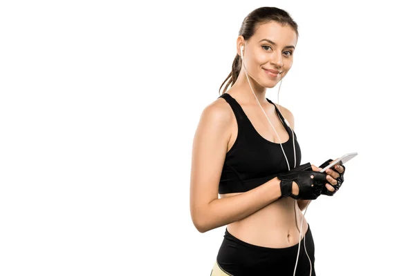 Attraktive Sportlerin in Gewichtheben-Handschuhen und Kopfhörern mit Smartphone isoliert auf weiß — Stockfoto