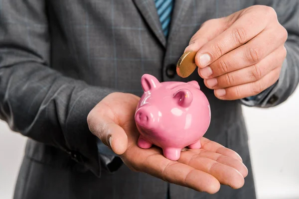 Close-up partial view of businessman holding piggy bank and coin isolated on white — Stock Photo