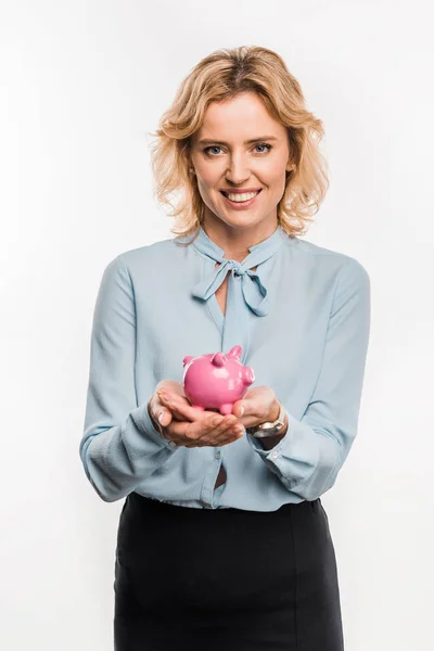 Beautiful businesswoman holding piggy bank and smiling at camera isolated on white — Stock Photo