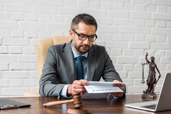 Серйозний чоловік-адвокат в окулярах, що працюють з контрактом в офісі — стокове фото