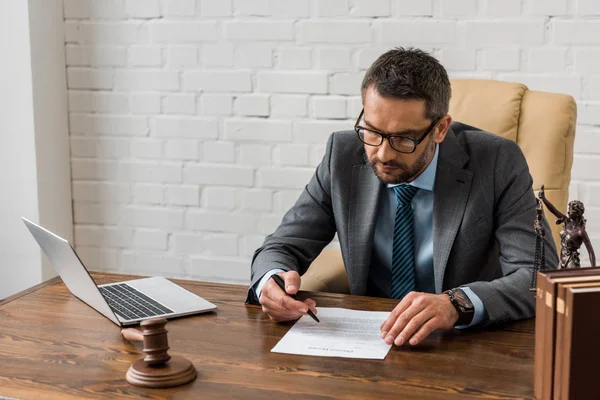 High angle view of concentrated male lawyer in eyeglasses working with document in office — Stock Photo