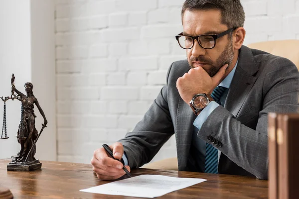 Fokussierter männlicher Anwalt mit Brille, der mit Vertrag im Büro arbeitet — Stockfoto