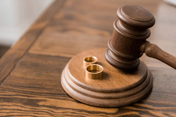 Vista de cerca del martillo juez y anillos de boda en la mesa de madera, concepto de divorcio - foto de stock