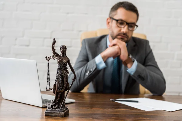 Vista de cerca de dama estatua de la justicia y abogado sentado detrás - foto de stock