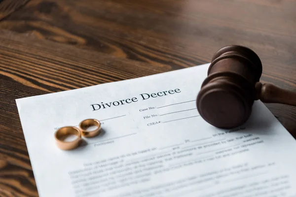 Divorce decree, wedding rings and judge hammer on wooden table — Stock Photo