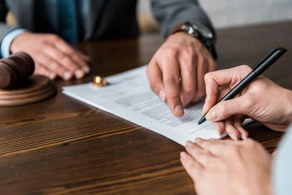 Abgeschnittene Aufnahme eines Richters, der auf Papiere zeigt und Klient unterzeichnet Scheidungsurteil — Stockfoto