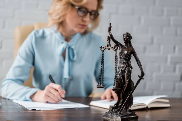 Крупним планом бачення статуї леді правосуддя та судді-жінки, що працюють позаду — стокове фото