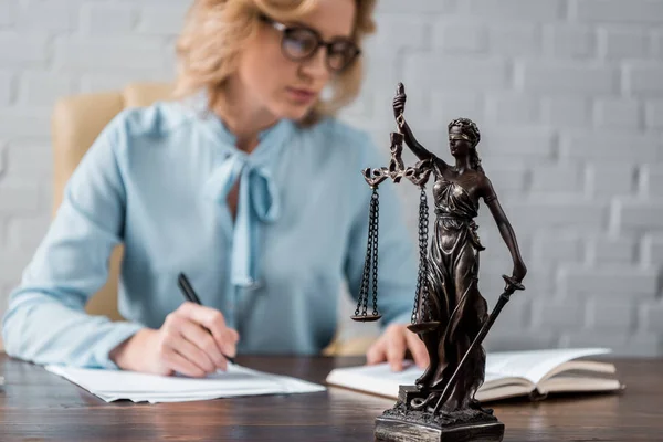 Vista de cerca de la estatua de la justicia dama y juez mujer que trabaja detrás - foto de stock