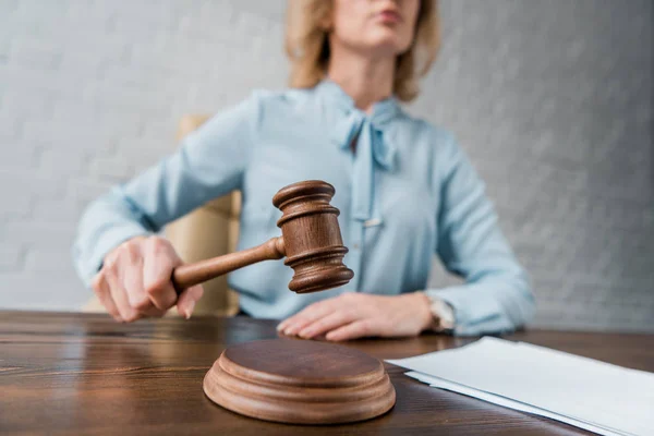 Cropped shot of female judge holding wooden hammer at workplace — Stock Photo