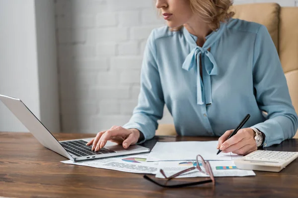 Colpo ritagliato di donna d'affari concentrata che lavora con documenti e computer portatile in ufficio — Foto stock