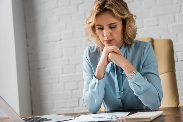 Mujer de negocios que trabaja con papeles y portátil en la oficina - foto de stock