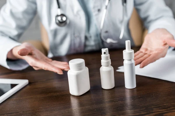 Inyección recortada de médico que muestra varios medicamentos al paciente en el consultorio - foto de stock