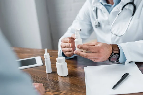 Tiro cortado de médico mostrando vários medicamentos para o paciente no escritório — Fotografia de Stock