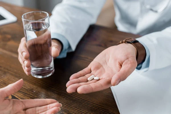 Cropped shot of doctor giving pills and water to patient at office — Stock Photo