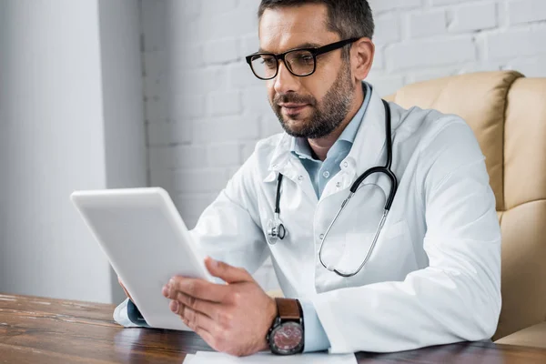 Schöne Ärztin arbeitet im Büro mit Tablet — Stockfoto