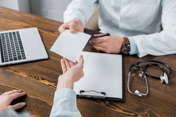 Colpo ritagliato del medico che dà la ricetta dei medicinali in bianco al paziente in ufficio — Foto stock