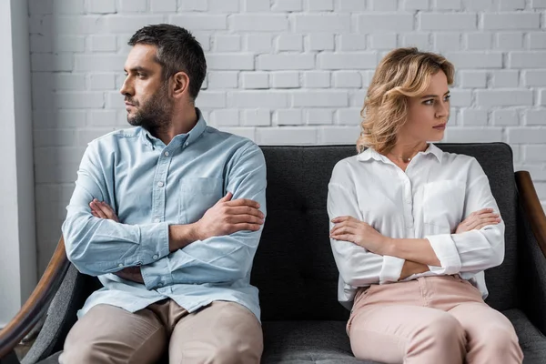 Mad couple sitting on couch after quarrel and looking away — Stock Photo