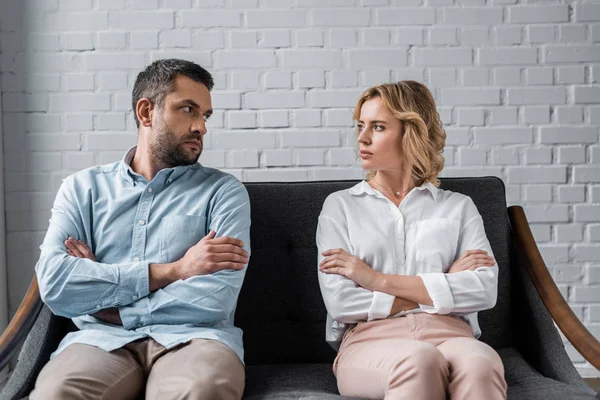 Couple sitting on couch after quarrel and looking at each other — Stock Photo