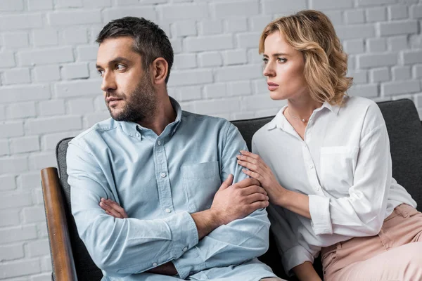 Woman talking to husband while sitting on couch after quarrel — Stock Photo
