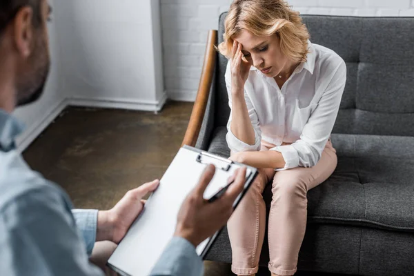 Mulher deprimida ter sessão de terapia psicóloga no escritório enquanto terapeuta segurando prancheta — Fotografia de Stock