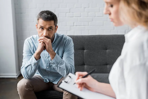 Hombre adulto triste en sesión de terapia psicológica en el consultorio - foto de stock