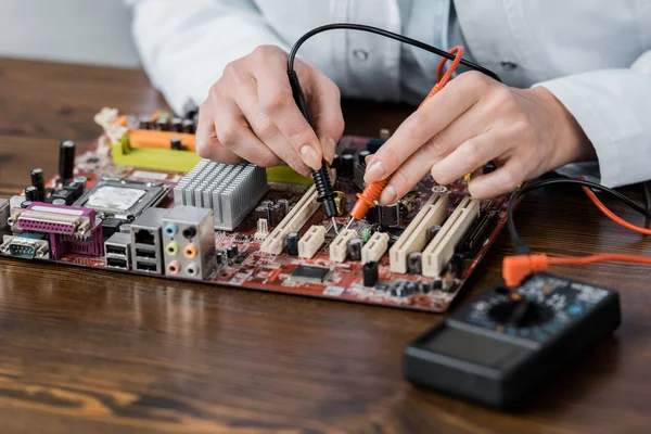 Tiro cortado de engenheiro elétrico com testador examinando placa-mãe do computador — Fotografia de Stock